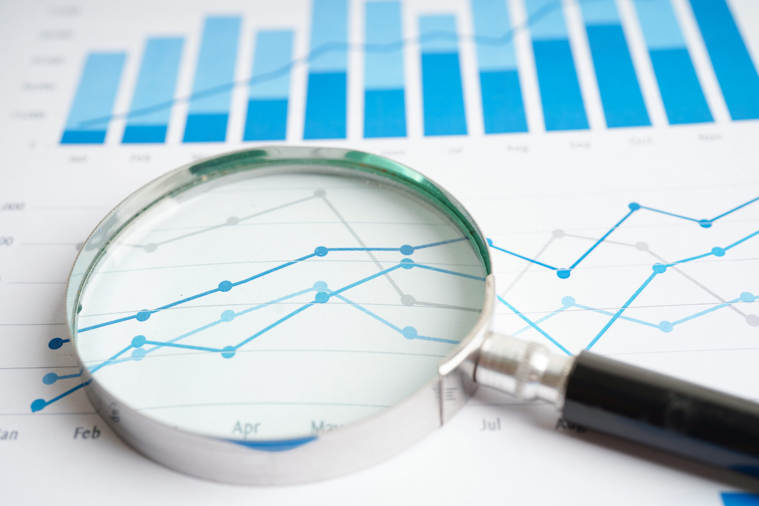 Magnifying glass examining financial charts and graphs